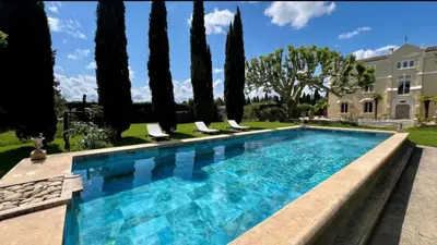 a swimming pool in front of a house with trees at CHATEAU 18e AVEC PISCINE in La Celle-sous-Gouzon