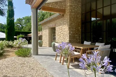 a patio with a wooden table and chairs and purple flowers at House for rent in Ménerbes Villa Carpe Diem in Ménerbes