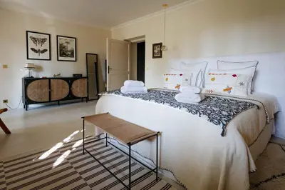 a bedroom with a large white bed and a table at Mas de La Lombarde Saint Rémy de Provence in Saint-Rémy-de-Provence