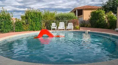 a swimming pool with a red apparatus in the water at Maison Les Demeures du Ventoux in Aubignan