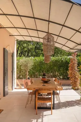 a wooden table and chairs on a patio with a chandelier at Spacious villa in Provence in Le Puy-Sainte-Réparade