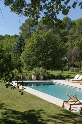 a swimming pool in a yard with benches and trees at Spacious villa in Provence in Le Puy-Sainte-Réparade