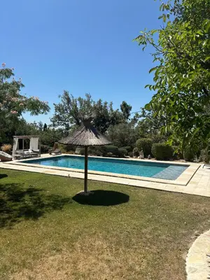 an umbrella in the grass next to a swimming pool at Estate in Provence in Aix-en-Provence