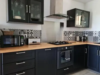 a kitchen with black cabinets and a stove top oven at mas des oliviers in Gordes