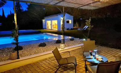 a table and chairs next to a swimming pool at night at Villa grand confort, piscine privée, petanque, pool house in Alleins