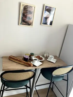 a wooden table with two chairs and a plate of food at Une Parenthèse Aixoise in Aix-en-Provence