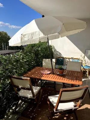 a wooden table with an umbrella and chairs at Une Parenthèse Aixoise in Aix-en-Provence