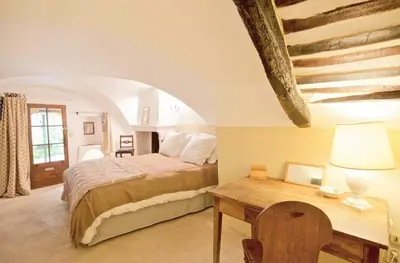 a bedroom with a bed and a wooden table at Stone House Within Castle Ramparts In Goult in Goult