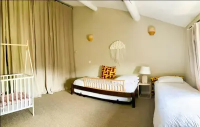 a bedroom with two beds and a crib at Stone House Within Castle Ramparts In Goult in Goult