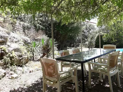 a glass table and chairs in a garden at agréable séjour en Luberon in Puget
