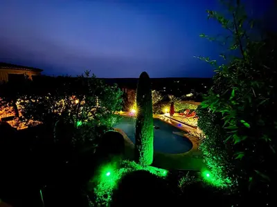 a night view of a swimming pool with green lights at Maison V in Ventabren