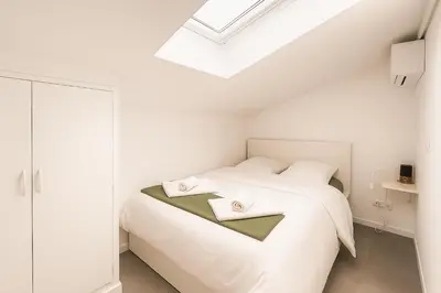 a white bedroom with a bed with two white pillows at T2 Duplex climatisé Suite et canapé-lit Aix centre in Aix-en-Provence