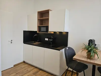 a kitchen with white cabinets and a sink and a table at La Bastide Foch - Appart'Hôtel Calme & Confort Centre Ville in Salon-de-Provence