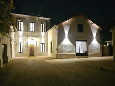 a large white building with lights on it at night at La Bastide Foch - Appart'Hôtel Calme & Confort Centre Ville in Salon-de-Provence