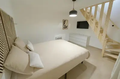 a white bedroom with a bed and a staircase at Charmant appartement au centre ville de Cavaillon in Cavaillon