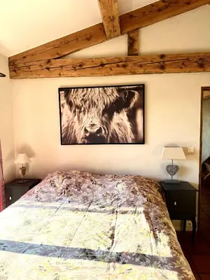 a bedroom with a bed with a picture of a cow on the wall at cheznico jas d la plane in Bédoin