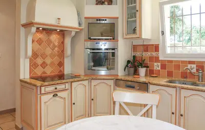 a kitchen with wooden cabinets and a stove top oven at Awesome Home In Saint Didier in Saint-Didier