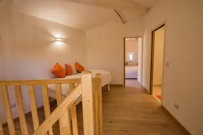 a bedroom with a bed and a wooden staircase at Maison de village au cœur d'Eyguières Alpilles in Eyguières