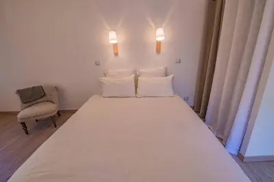 a bedroom with a large bed with white sheets and pillows at Maison de village au cœur d'Eyguières Alpilles in Eyguières