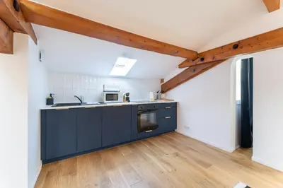 a kitchen with black cabinets and wooden floors at Design & Cozy, 10 meters from Cours Mirabeau, AC in Aix-en-Provence