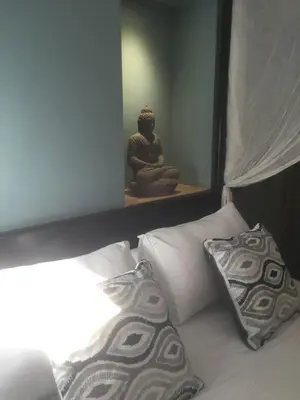 a bed with two pillows and a buddha in a room at AJOUCADOU premiere loge in Lourmarin