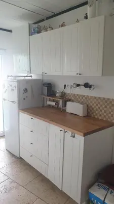 a kitchen with white cabinets and a wooden counter top at Petite maison sur Apt in Apt