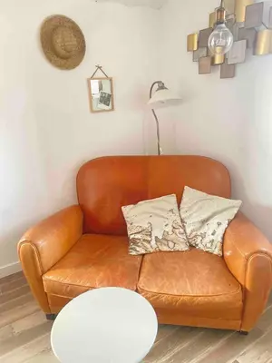 a brown leather couch in a living room with a table at Cocon cosy et calme au coeur du centre historique in Aix-en-Provence