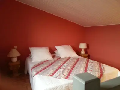 a bedroom with a bed with red walls and two lamps at La Petite Maison de Marie Louise in Lauris
