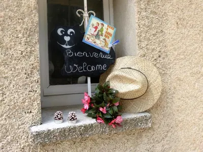a window with a straw hat and flowers on a window sill at La Petite Maison de Marie Louise in Lauris