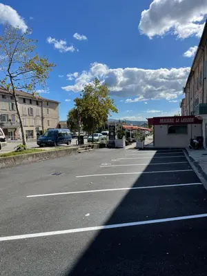 an empty parking lot with a building and a sky at Hôtel La Lavande in Carpentras