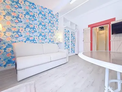 a white couch in a living room with a floral wall at Tiny house Cécile en Avignon in Avignon
