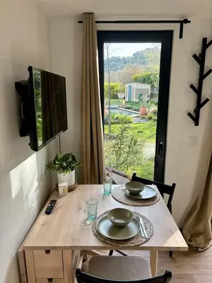 a wooden table with two plates on it in front of a window at Studio tout confort dans la campagne aixoise in Le Puy-Sainte-Réparade