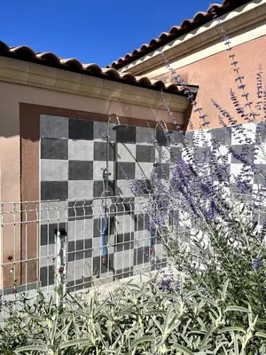 a cat behind a fence in front of a tile wall at Charming house, Lubéron, near golf and wineries in Pierrevert