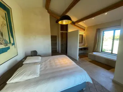 a bedroom with a bed and a window and a tub at Le Jas à Goult in Goult