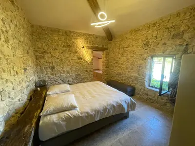 a bedroom with a bed and a stone wall at Le Jas à Goult in Goult