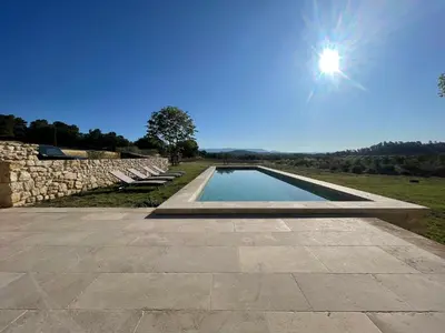 a swimming pool in a field with the sun in the sky at Le Jas à Goult in Goult