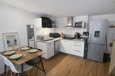 a kitchen with white cabinets and a stainless steel refrigerator at Le Breizh'Aix - Joli duplex au cœur du centre ville d'Aix-en-Provence avec jardin in Aix-en-Provence