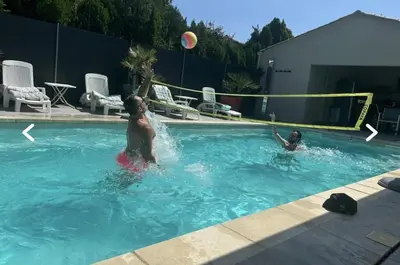 two people playing with a volley ball in a swimming pool at Charmante Maisonnette T3 avec Jardin Privé in La Motte-dʼAigues