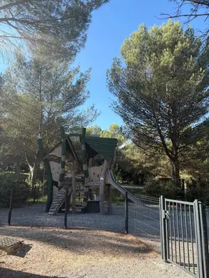 a slide in a park behind a fence at Appartement domaine de Pont Royal in Mallemort