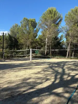 a tennis court with a fence and trees at Appartement domaine de Pont Royal in Mallemort