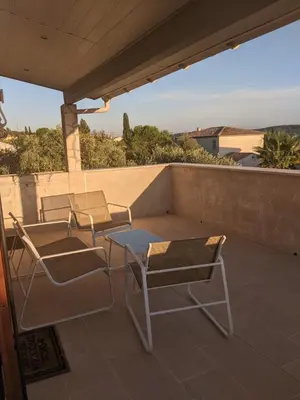 a patio with two chairs and a table on a roof at Maison 3 pièces avec jardin et terrasse in La Fare-les-Oliviers