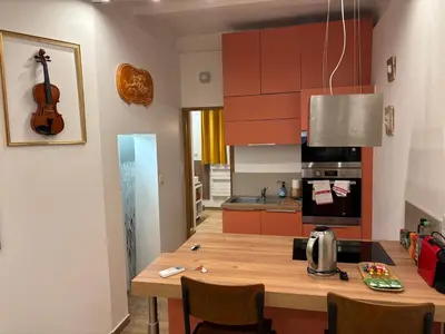 a kitchen with a wooden table and a guitar on the wall at Appartement Turandot, 1 chambre, près du Cours Mirabeau in Aix-en-Provence