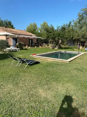 a shadow of a person standing next to a swimming pool at La Roussillonnaise in Roussillon