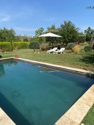 a swimming pool with two chairs and an umbrella at La Roussillonnaise in Roussillon