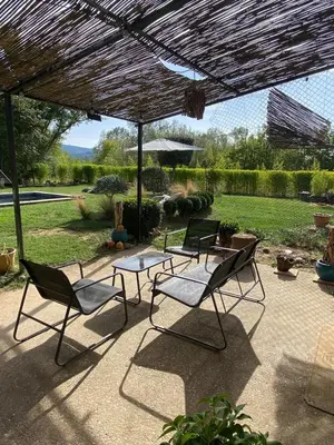 a patio with chairs and a table and an umbrella at La Roussillonnaise in Roussillon