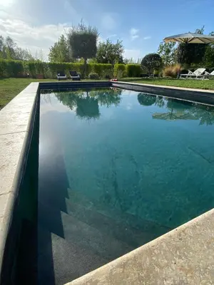 a swimming pool with blue water in a yard at La Roussillonnaise in Roussillon
