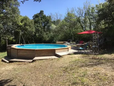 a swimming pool in a yard with a red umbrella at Belle villa avec piscine, belle vue, calme absolu in Apt