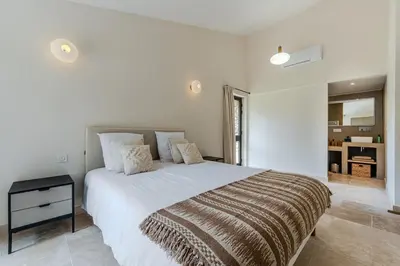 a white bedroom with a large bed and a window at Magnifique villa au coeur de la campagne de Gordes in Gordes