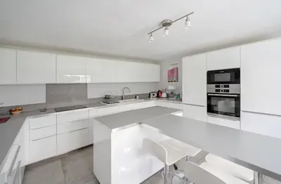 a white kitchen with white cabinets and a table at mas de la bergerie in Cavaillon