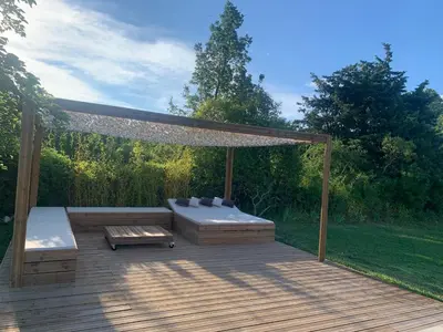 a wooden deck with a bench and a canopy at mas de la bergerie in Cavaillon